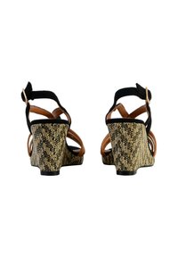Black and tan wedge sandals with a woven texture, featuring multiple cross straps and a rear ankle strap with a gold-tone buckle.