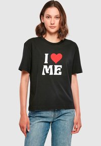 Juodas medvilninis marškinėliai su baltu ir raudonu užrašu "Aš ♥ save." Trumpomis rankovėmis ir apvaliu iškirpimu. Laisvas siluetas, su lygiu paviršiumi.