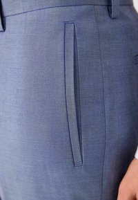 Tailored blue trousers with a textured fabric, featuring a single side pocket with a sleek design and contrasting stitching detail.