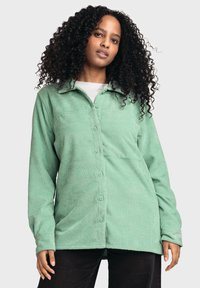 Green corduroy button-up shirt with a collar, featuring vertical ribs, long sleeves, and visible buttons down the front.
