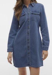 Denimklänning, lång ärm, knappar framtill, två bröstfickor, mörkblå färg, mjuk textur, något avsmalnande design.