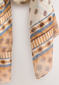 Patterned scarf in cream, orange, and blue. Features geometric designs and florals with smooth, lightweight fabric and a rippled texture.