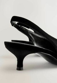 Tocuri slingback negre, realizate din material catifelat, cu un toc subțire și curbat și un interior neted pentru confort.