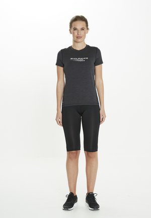 Mörkgrå atletisk t-shirt med texten "ENDURANCE" över bröstet, i kombination med svarta åtsittande shorts och svarta sportskor. Slät textur.