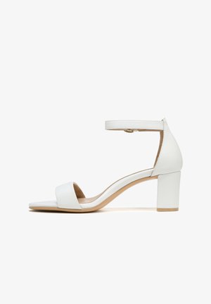 Sandale blanche à talon carré avec une large lanière avant et une bride de cheville réglable, présentant une texture en cuir lisse et une semelle de couleur tan.