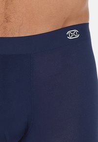 Herrenbrief in Marineblau aus strukturiertem Stoff mit einem glatten Bund und einem weißen Logodetail.
