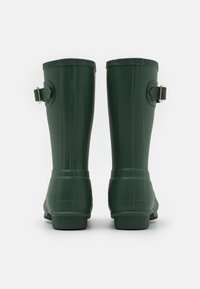 Botas de lluvia de goma verdes con una textura suave, caña recta y detalle de hebilla ajustable plateada a cada lado. Suela de goma plana.