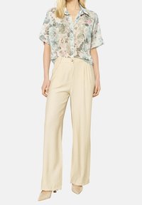 Floral, short-sleeve, button-up shirt with blue buttons; beige, high-waisted, wide-leg trousers; smooth texture; pastel colors.
