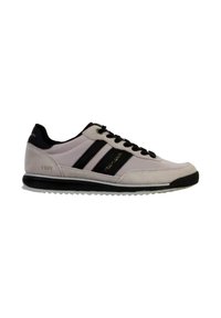 Sneakers in suede grigio chiaro con strisce e lacci neri. Presentano una suola testurizzata e un marchio dorato. L'anno "1989" stampato in oro sul lato.