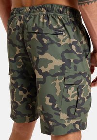 Cargo šortky v maskáčovom vzore majú zelené a béžové odtiene, elastický pás, bočné vrecká a hladký povrch.