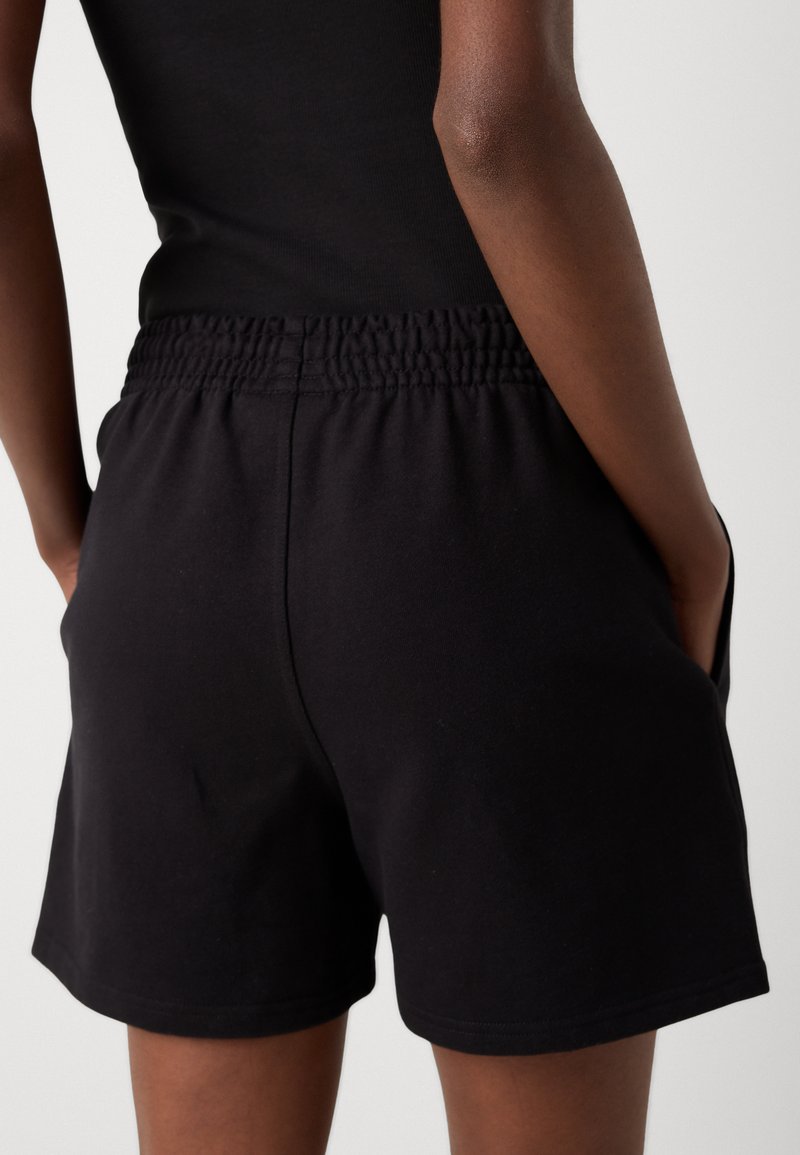 Zwarte katoenen shorts met een elastische tailleband, zijzakken en een gladde textuur, gestileerd met een eenvoudige, klassieke snit.