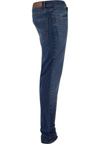 Tummansiniset farkut, joissa on slim fit -leikkaus. Niissä on takatasku, suora lahje ja hienovarainen haalistunut kuvio kankaassa.