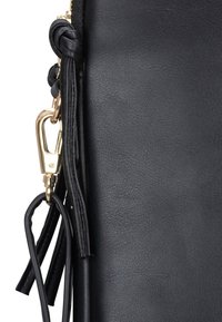 Schwarze Lederhandtasche mit strukturierter Oberfläche, ausgestattet mit einem goldenen Metallverschluss und geflochtenen Lederdetails an der Seite. Lange dekorative Quasten.