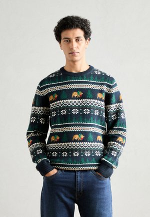 Marineblauwe gebreide trui met een geometrisch patroon van beren, bomen en sneeuwvlokken in groen, geel en rood. Geribbelde mouwen en halslijn.