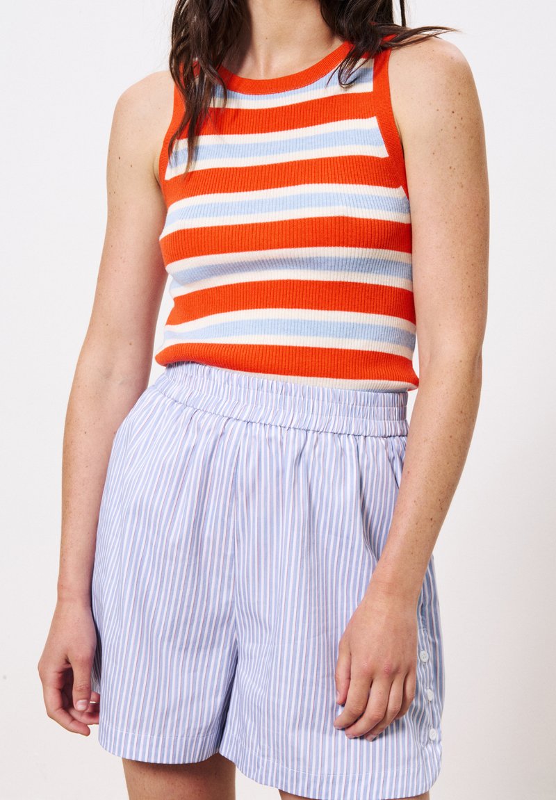 Débardeur rayé rouge et bleu à côtes, associé à un short à rayures bleu clair avec une taille élastique et des accents de boutons.