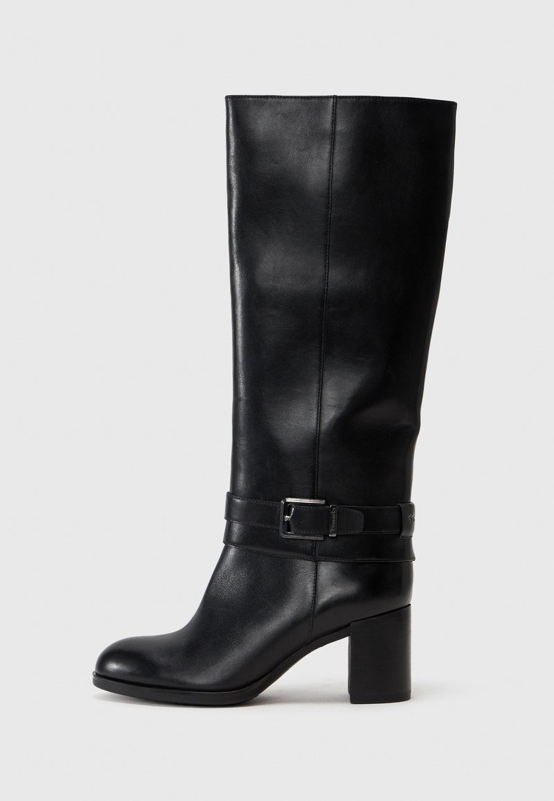 Botte en cuir noire montant jusqu'aux genoux avec talon carré et bride décorative à boucle autour de la cheville, vue de profil sur un fond uni.