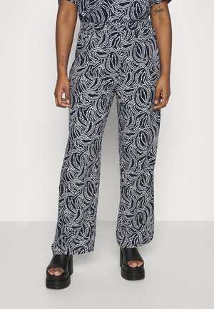 Mörkblå vida byxor med ett vitt swirl-mönster, tillverkade av lätt tyg. Har resårmidja och bärs tillsammans med svarta platåsandaler.