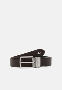 Brun perforerad läderbälte med en silverfärgad rektangulär spänne. Har en Lacoste-logotyp präglad på remmen.