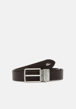 Brown perforated leather belt with a silver rectangular buckle. Features a Lacoste logo embossed on the strap.