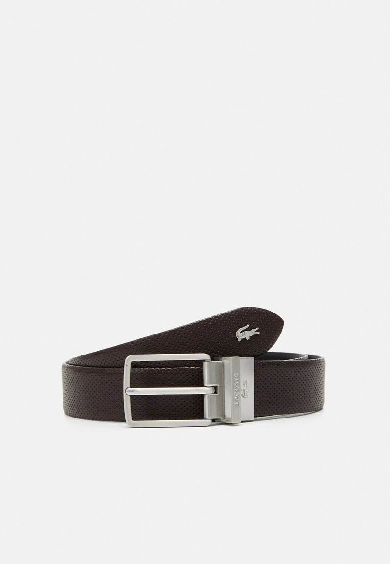 Cinturón de cuero marrón perforado con una hebilla rectangular de plata. Presenta un logo de Lacoste estampado en la correa.