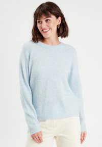 Suéter esponjoso de color azul claro, con cuello redondo y mangas largas, que presenta puños y dobladillo acanalados en una suave tela texturizada.