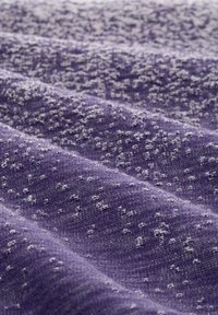 Lila strukturierter Stoff mit weichem Gewebe, der ein Muster aus erhabenen Punkten aufweist und dadurch eine subtile Tiefe und Variation in der Oberflächendetaillierung schafft.