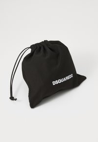 Bolsa de tela negra con cordón en la parte superior, que presenta el logo blanco "DSQUARED2". Textura suave, forma compacta, diseño minimalista.