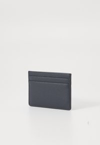 Mėlynos odos kortelių laikiklis su tekstūruotu paviršiumi, turintis keturias kortelių vietas ir ploną dizainą. Be matomų metalinių detalių ar puošmenų.