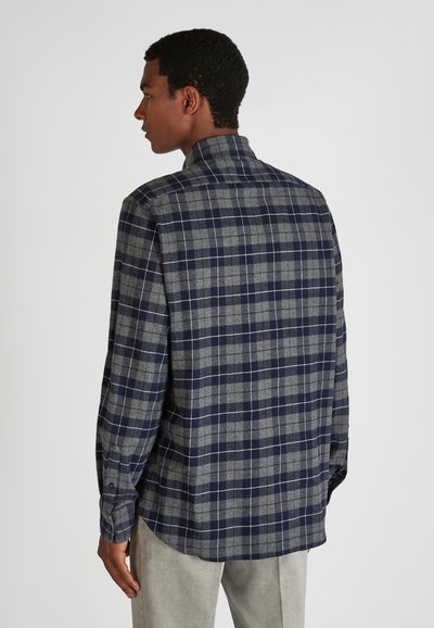 Camisa a rayas en tonos azul marino y gris con cuello, mangas largas y dobladillo curvado. El material parece suave y texturizado.