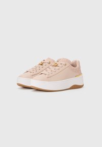 Low platform sneakers in soft pink with gold logo charm on laces, patterned heel collar, and white thick soles with brown tread.