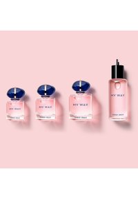 Fire Giorgio Armani "My Way" parfymeflasker i forskjellige størrelser plassert på rad på en rosa bakgrunn.