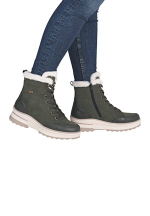 Dark green ankle boots with white faux fur lining, padded collar, and a beige platform sole. Features laces and a side zipper.