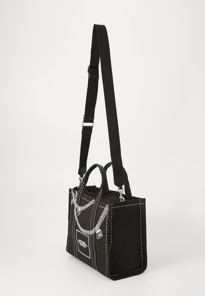 Schwarze Canvas-Handtasche mit weißen Nähten, ausgestattet mit zwei kurzen Griffen, einem verstellbaren Schultergurt und Kettendesigns auf der Vorderseite.