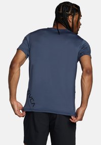 Camiseta deportiva azul hecha de material que absorbe la humedad, con cuello redondo, mangas cortas y detalle del logo negro en el lado inferior.