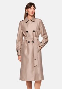 Beiger Trenchcoat mit glattem Satin-Finish. Verfügt über doppelte Knopfreihen, einen abnehmbaren Gürtel und Seitentaschen.