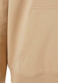 Felpa beige con tasca a marsupio, polsini e orlo a coste. Realizzata in tessuto testurizzato con una finitura morbida.