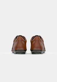 Brown leather shoes with a rounded shape and black rubber soles. Features a smooth texture and a subtle seam detail at the heel.