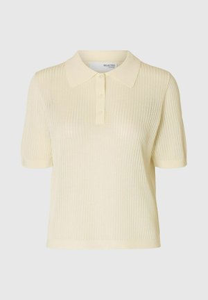 Šortsu piedurkņu bālgans dzeltenais polo krekls ar ribotu tekstūru, kuram ir mīksts apkakle un trīs pogu aizdare. Izgatavots no viegla adīta materiāla.