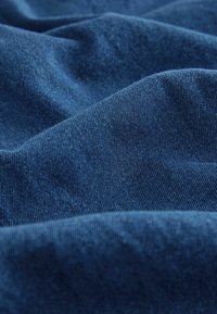 Tmavě modrý textil s měkkou texturou a jemným leskem, s hladkými, plynulými vráskami a jemným, rovnoměrným tkaním.