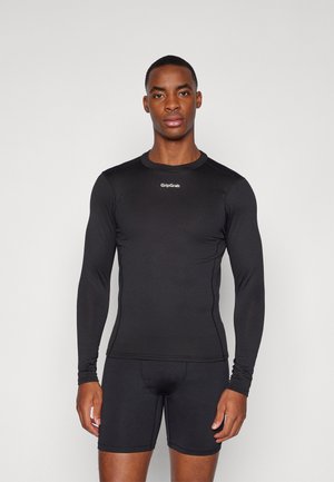 Chemise de sport noire à manches longues avec un tissu texturé, col rond et logo GripGrab sur la poitrine, associée à un short de compression noir.