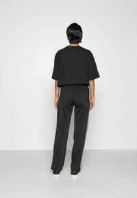 Czarny bawełniany t-shirt w oversize z krótkim rękawem, w połączeniu z czarnymi spodniami dresowymi z białymi paskami po bokach i elastycznym paskiem w talii.