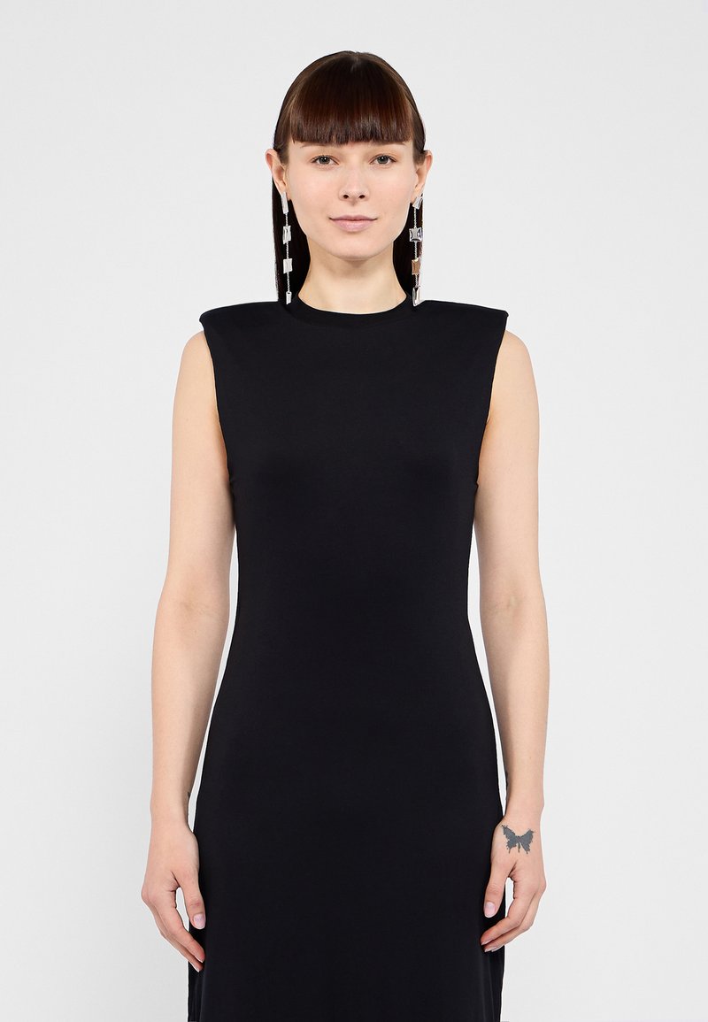 Black sleeveless dress with structured shoulder design, smooth texture, and fitted silhouette. Long, straight cut with side slits.