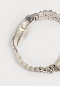 Sølv metal armbåndsur med en rund urskive, en struktureret bezel, kædearmbånd og en krone på siden til justering af tid.