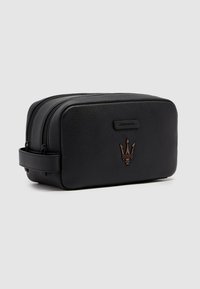 Zwarte leren toilettas met een gestructureerde afwerking, dubbele ritssluitingen en een bronzen logo-accent aan de voorkant. Voorzien van een zijhandvat.