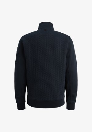 Jakna tamnoplave boje s teksturiranim prošivenim stražnjim panelom, visokim ovratnikom, dugim rukavima i malim džepom na lijevoj ruci.