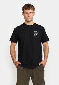 Zwart katoenen t-shirt met een witte grafische print op de linker borst. Korte mouwen en een klassiek ronde halsvorm.