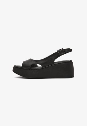 Sandali wedge in pelle nera con design a punta aperta, strap regolabile e suola texturizzata con una piattaforma alta per un'altezza extra.