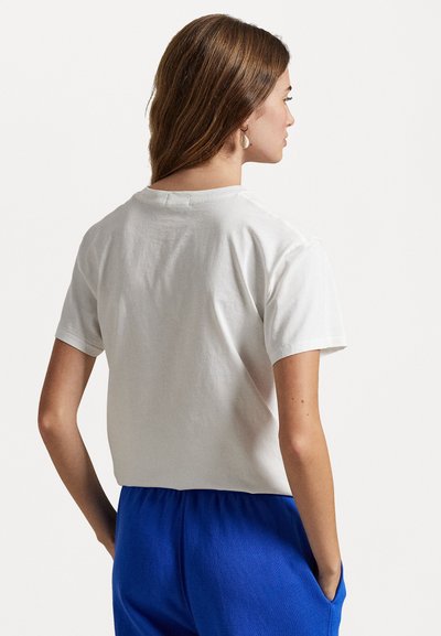 Balta medvilninė marškinė su trumpomis rankovėmis ir apvaliu iškirpimu, pasižyminti laisvu siluetu ir švariu, paprastu dizainu.