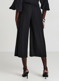 Culotte nere a gamba larga con vita elastica. Tessuto liscio, lunghezza corta e abbinate a sandali con tacco alto e cinturini.