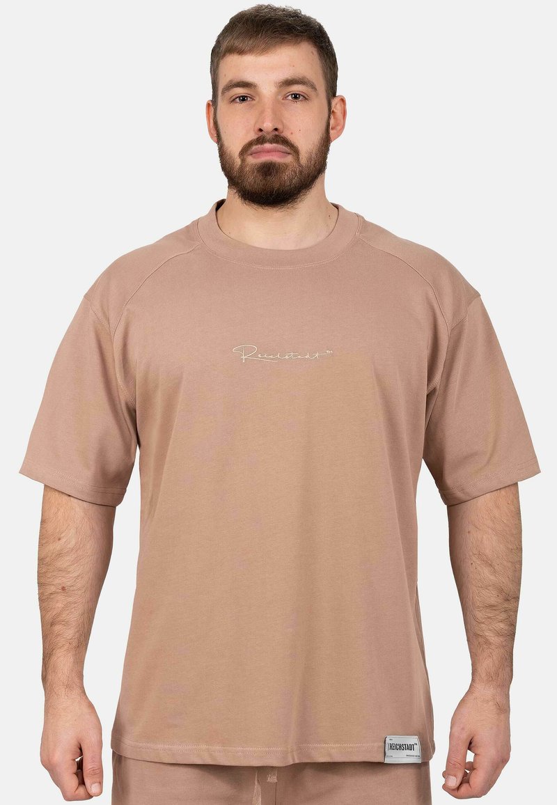 T-shirt à manches courtes, coupe ample en coton beige clair. Comprend un petit logo brodé et un col arrondi.